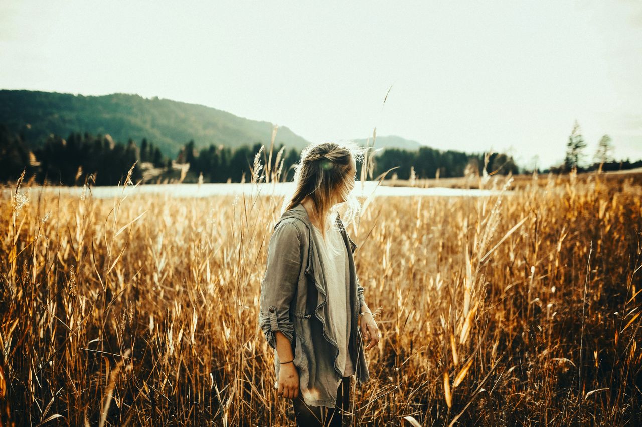 A woman enjoying the serene beauty of a golden wheat field at sunset in rural Germany.